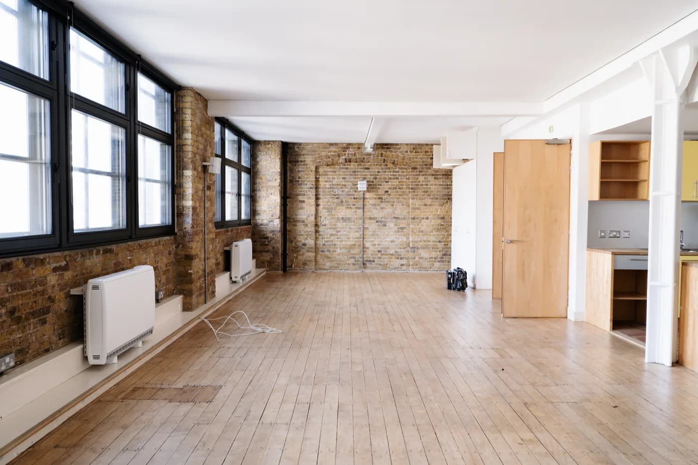Open-plan warehouse space before renovation, bare brick and dated finishes