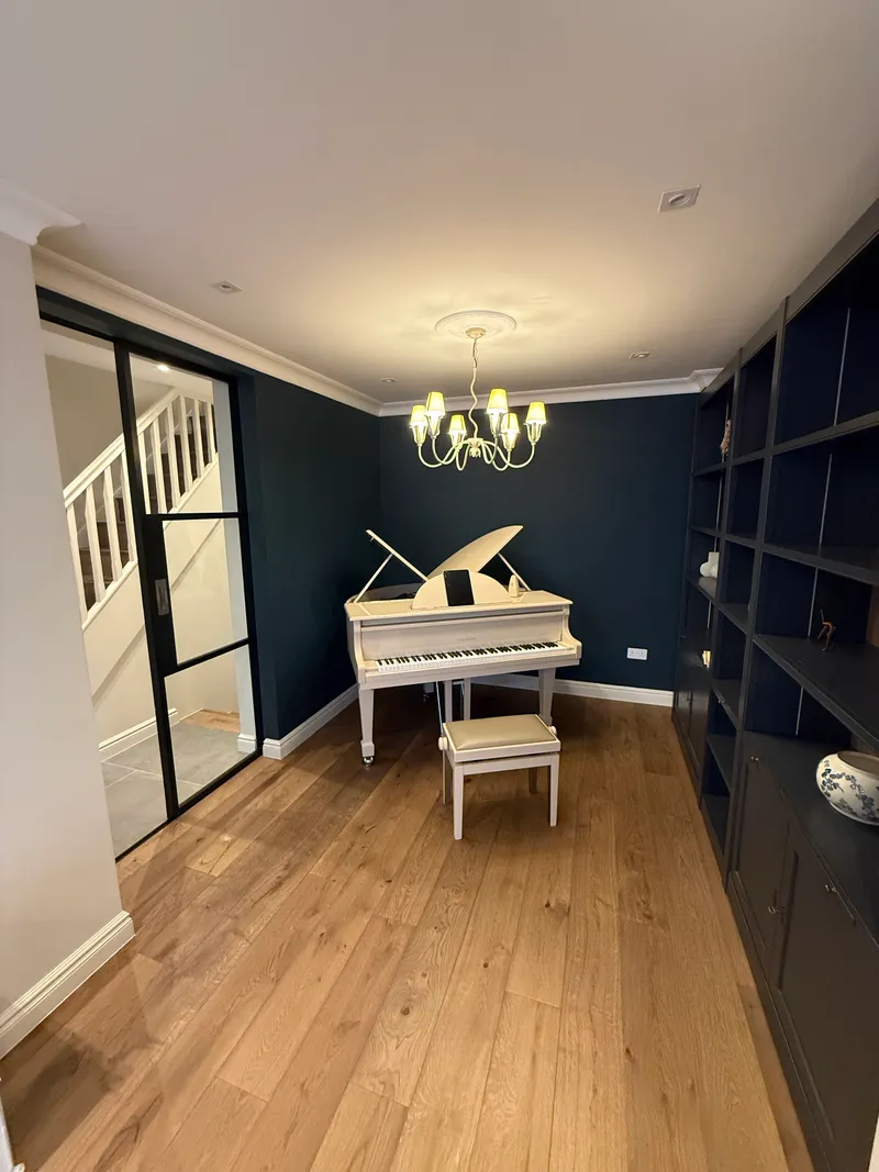 Navy music room with grand piano and built-in shelving